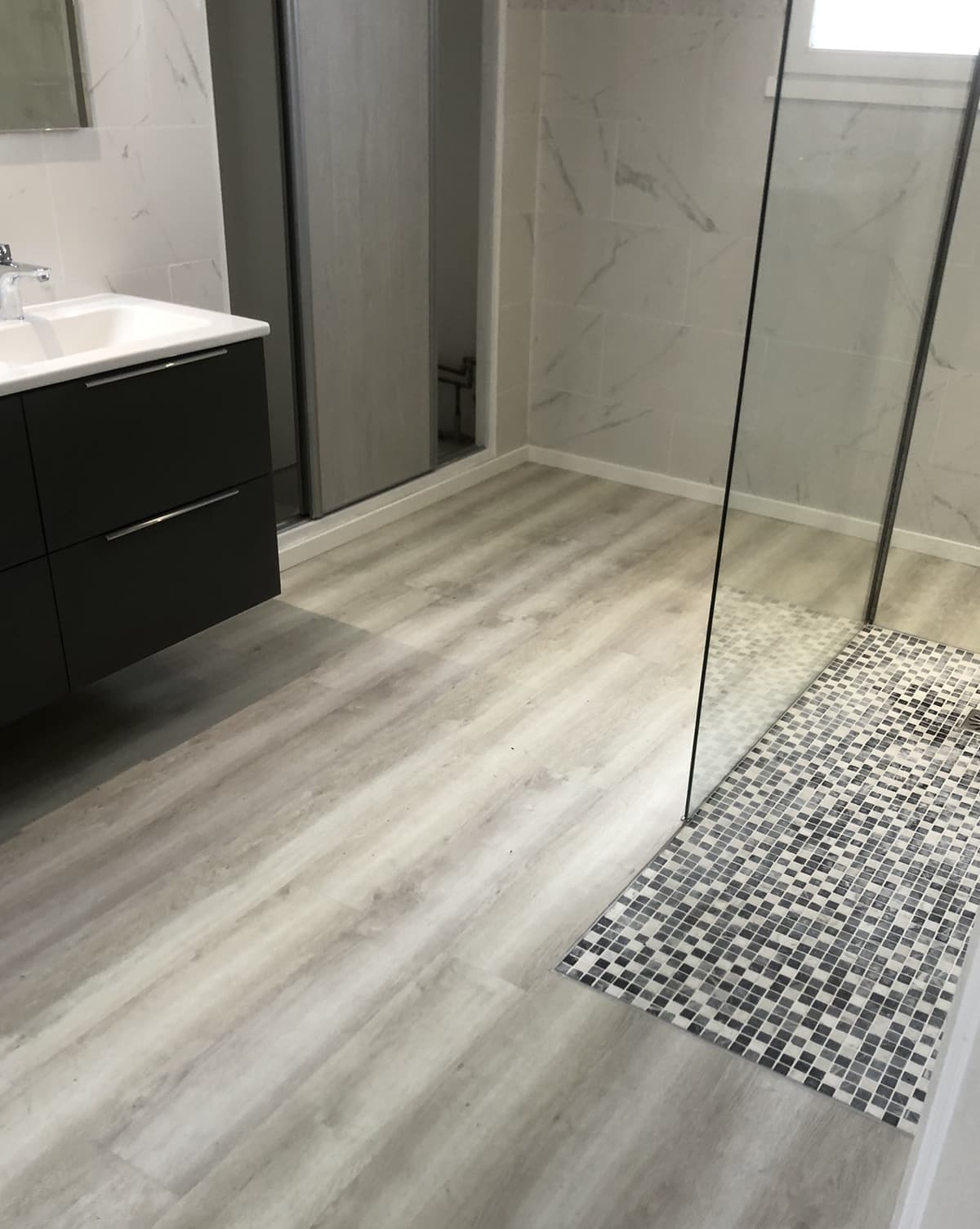 Sol imitation bois gris dans une salle de bain avec douche à l’italienne