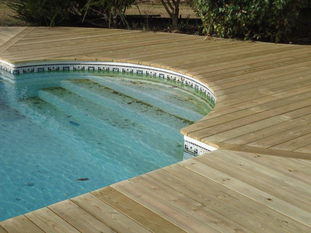 Plage de piscine en bois épousant la forme arrondie du bassin