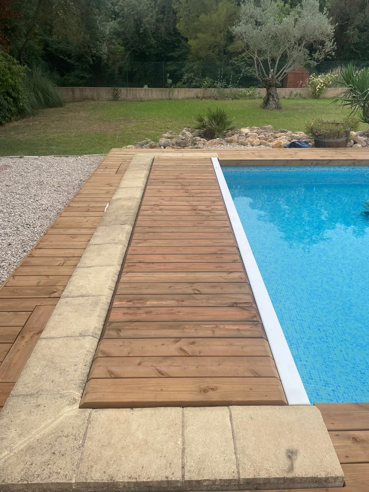 Plage de piscine associant bois et margelles en pierre
