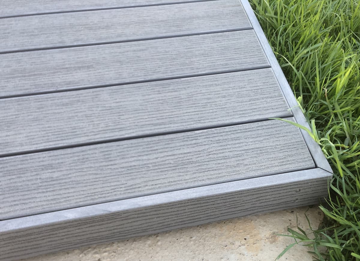 Terrasse en lames composites grises devant une baie vitrée