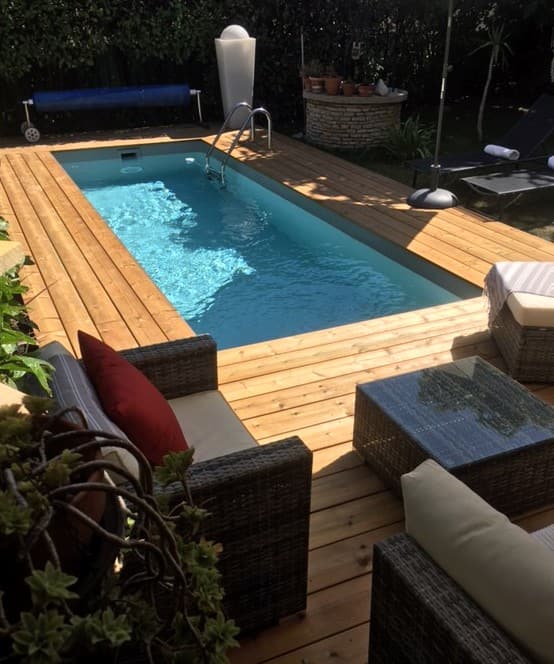 Terrasse bois autour d’une piscine avec salon de jardin